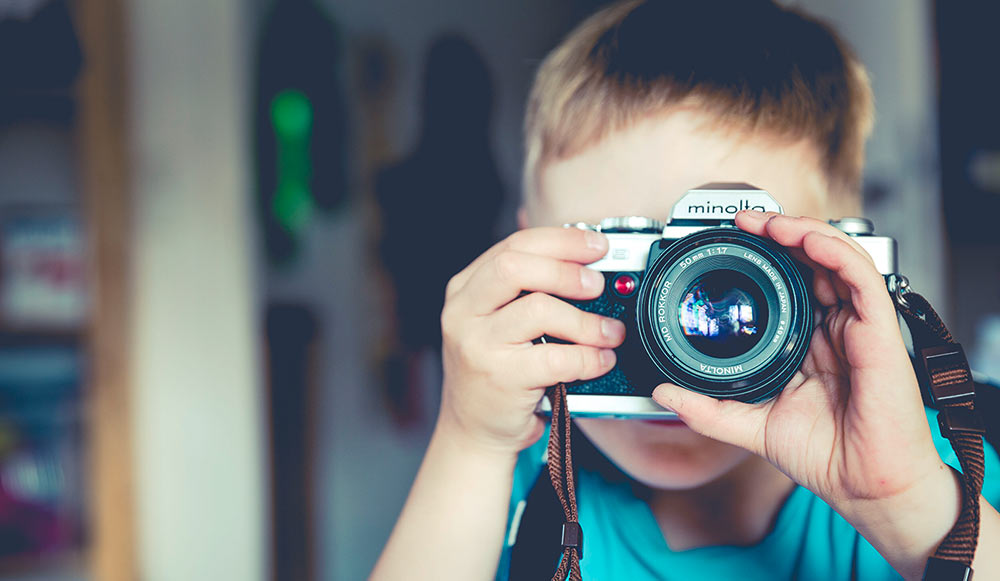 A picture of a boy that takes a picture with an old fashion camera